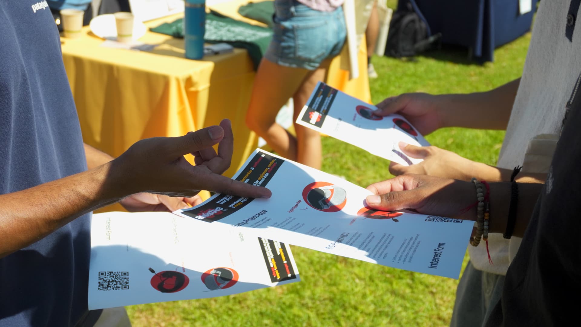 Members handing out project flyers with interest-form QR codes at a campus event